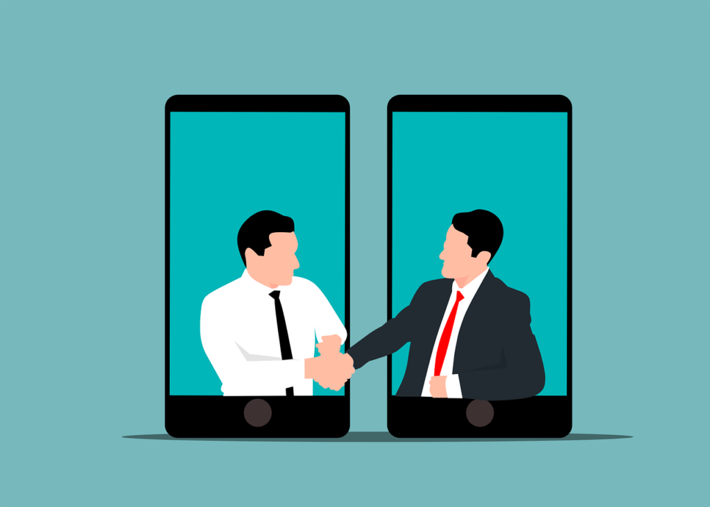 Two businessmen appearing from smartphone screens shaking hands, representing digital partnerships and online business growth through SEO services in Surat.